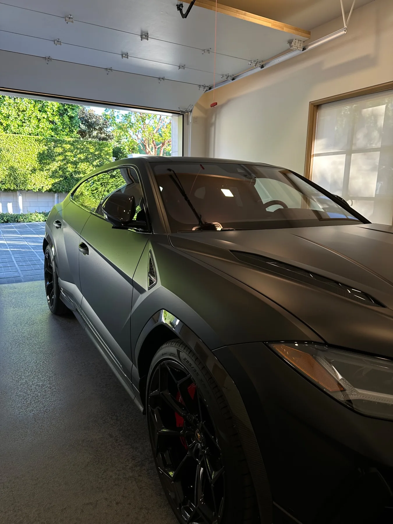 Matte black Lamborghini Urus with dark window tint in a garage