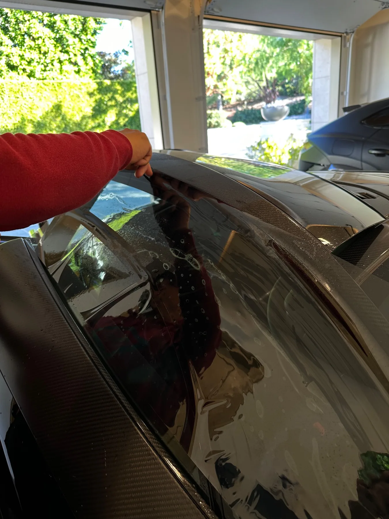 Professional installer applying tint film to a McLaren window