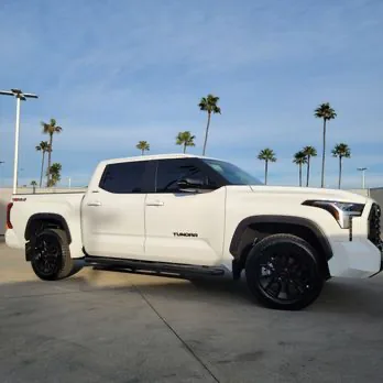 White Toyota Tundra with dark window tint by palm trees